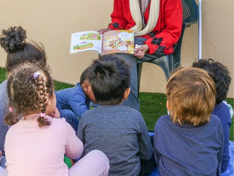 elderly woman reading to children